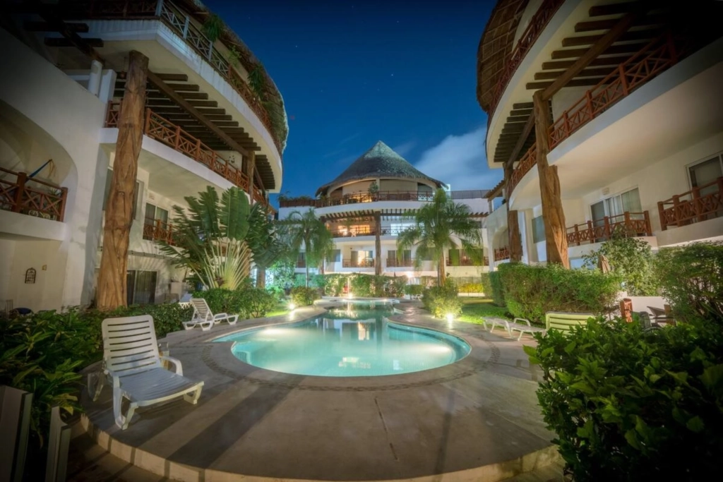 Relájate junto a la piscina en un entorno tropical tranquilo en Playa del Carmen Piscina exterior rodeada de jardines tropicales en una residencia de Playa del Carmen
