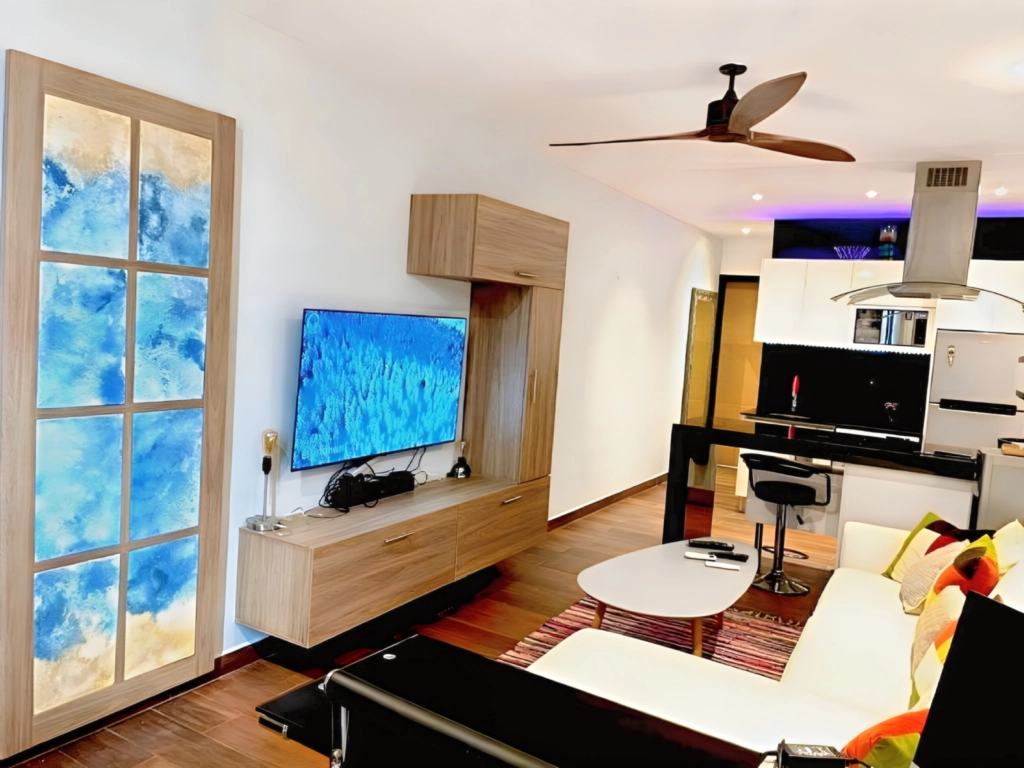 Modern Living Room & Open Kitchen – Vedra Suite Playa del Carmen Modern living room with Smart TV, comfortable sofa and open-plan kitchen at Vedra Suite in Playa del Carmen