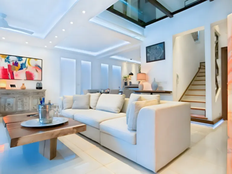 Un salón contemporáneo y luminoso, diseñado con un ambiente elegante y acogedor. Salón luminoso y elegante con sofás blancos, mobiliario contemporáneo y grandes ventanales.
